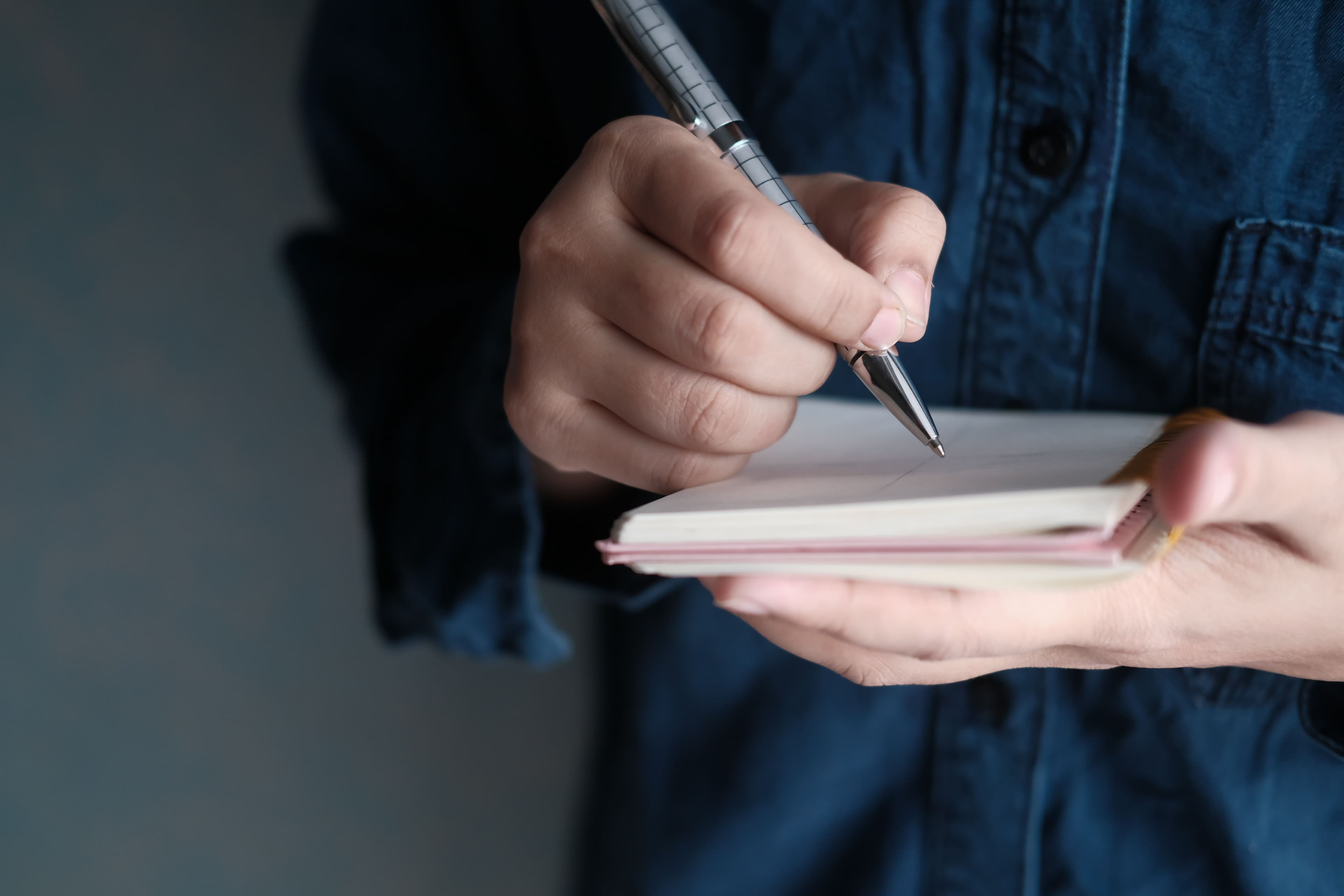 Hands writing in a notebook with a pen, capturing a moment of creativity and focus.
