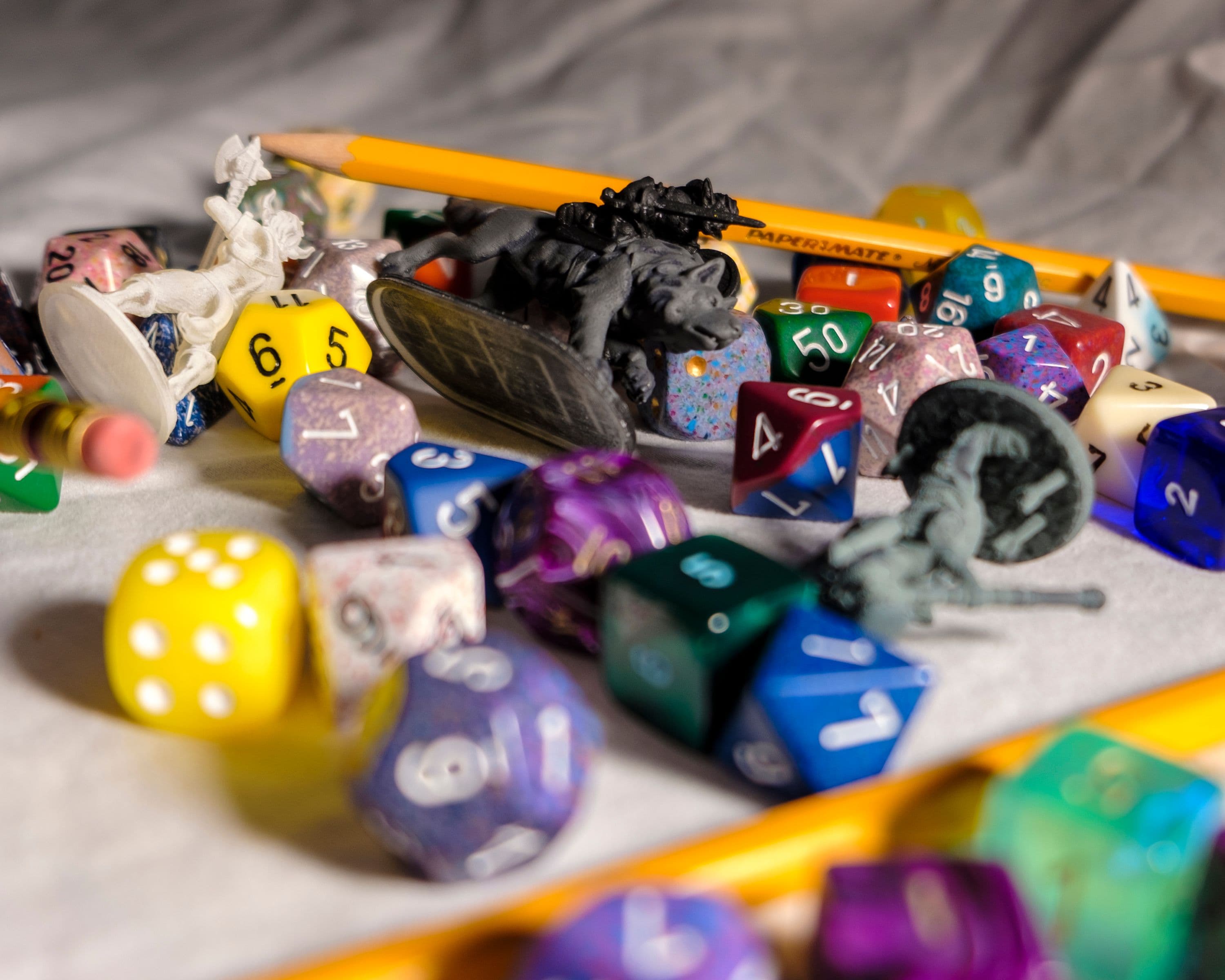 High angle of color dices in different shapes scattered on table with small toy animals and pencils during game