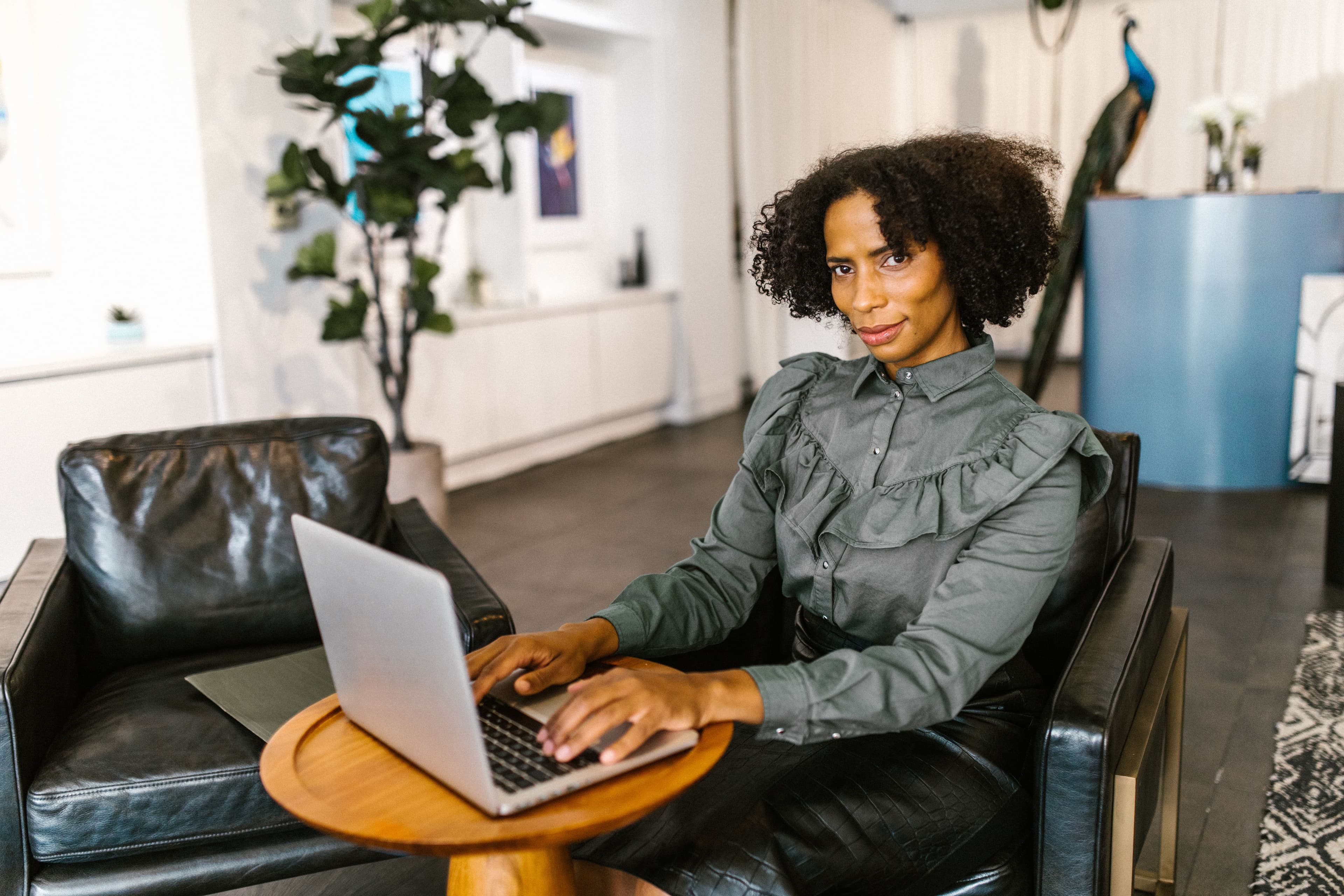 Confident businesswoman with afro hair typing on laptop seated in a modern office.