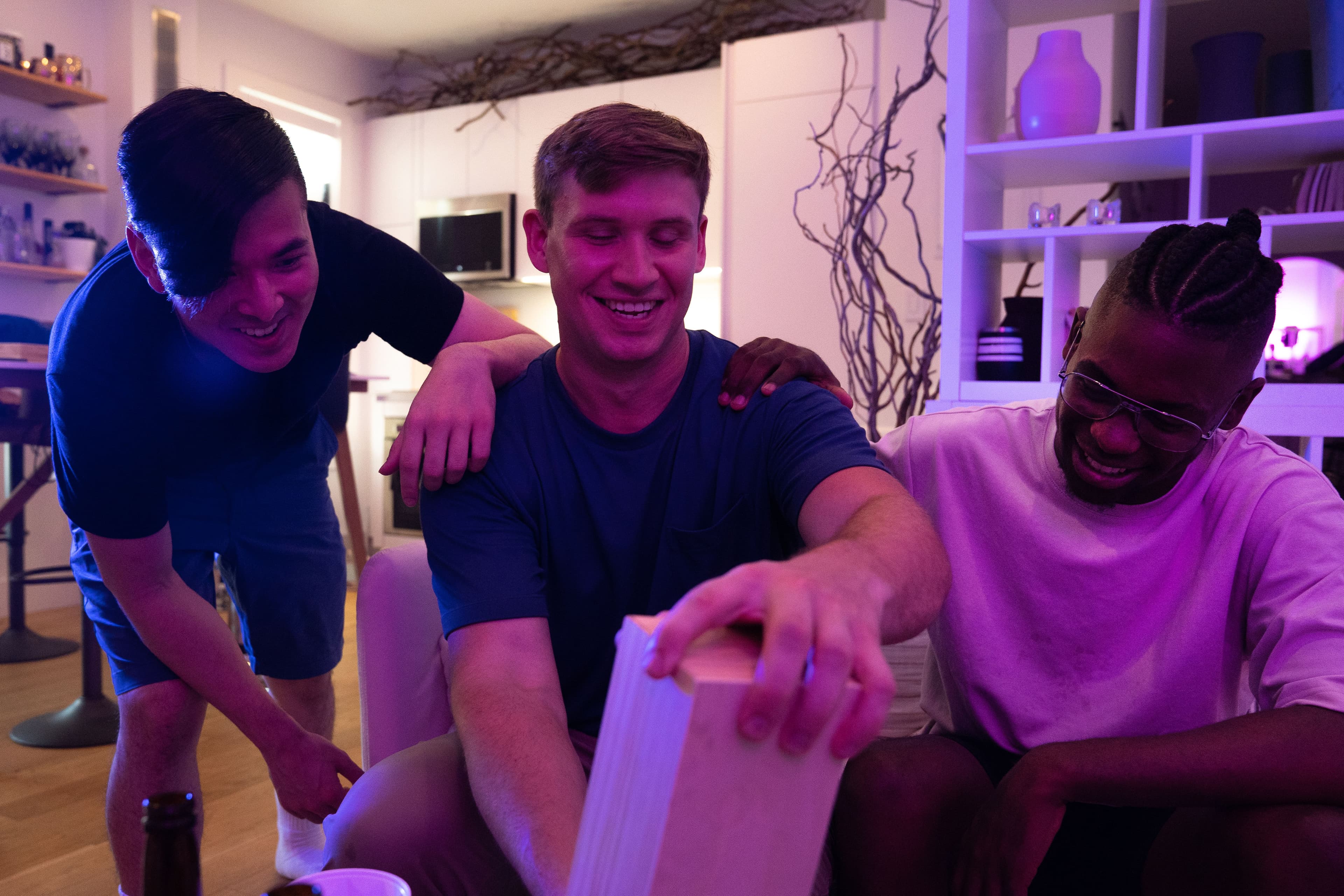 Three friends enjoying a fun game night together indoors with laughter and smiles.