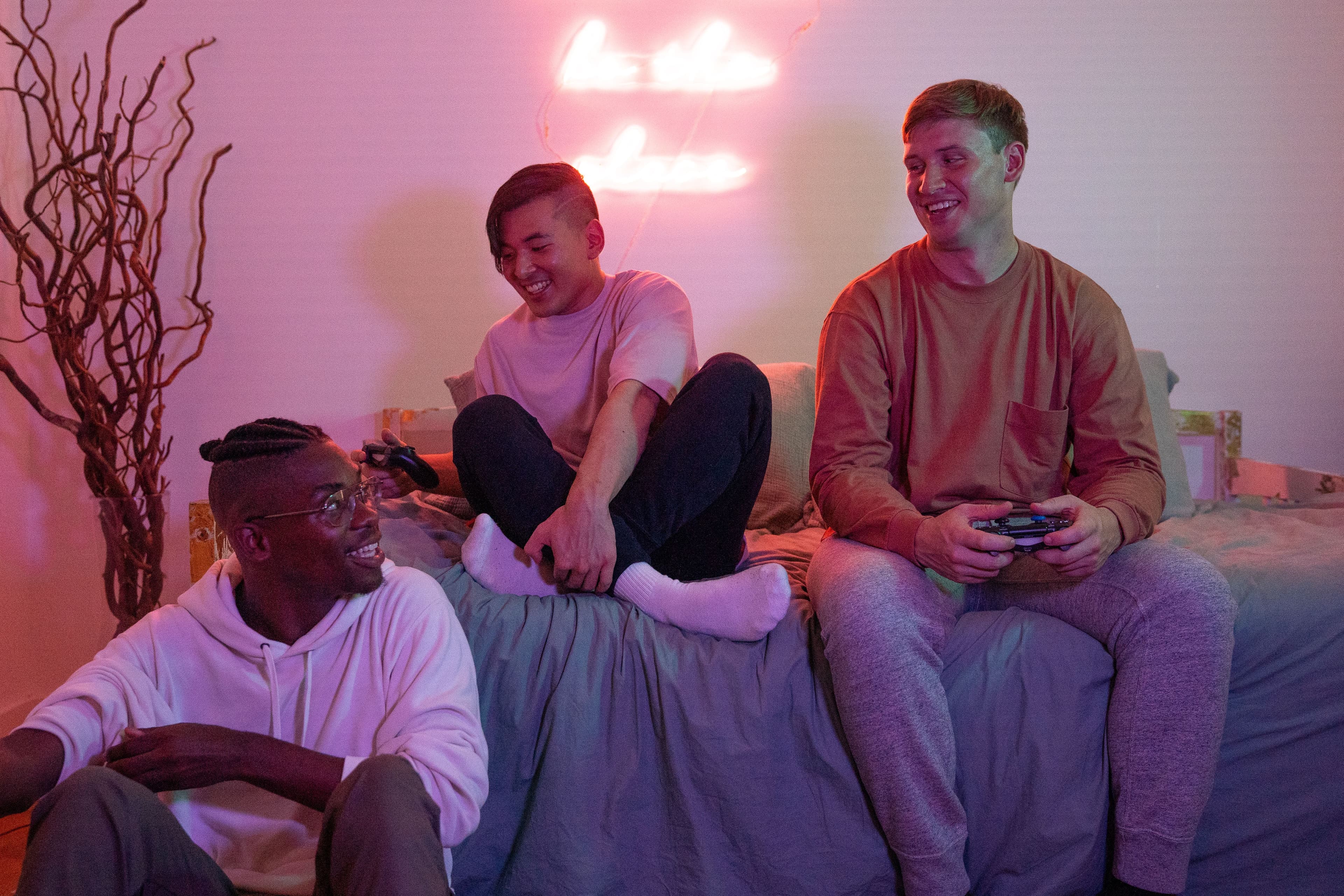 Three diverse friends joyfully playing video games together in a cozy room setting.