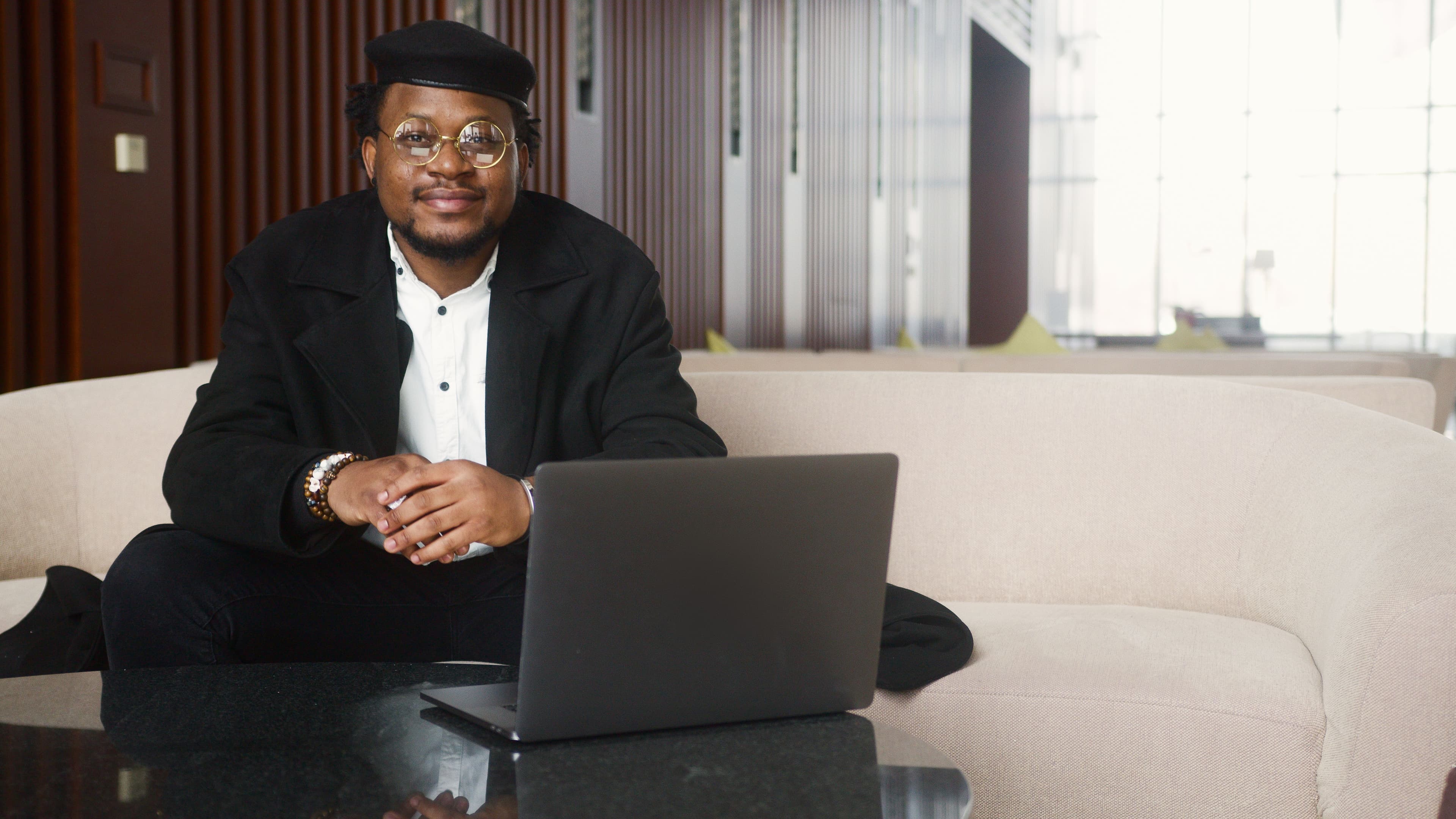 A cheerful freelancer sitting on a couch with a laptop, exuding professionalism and comfort.