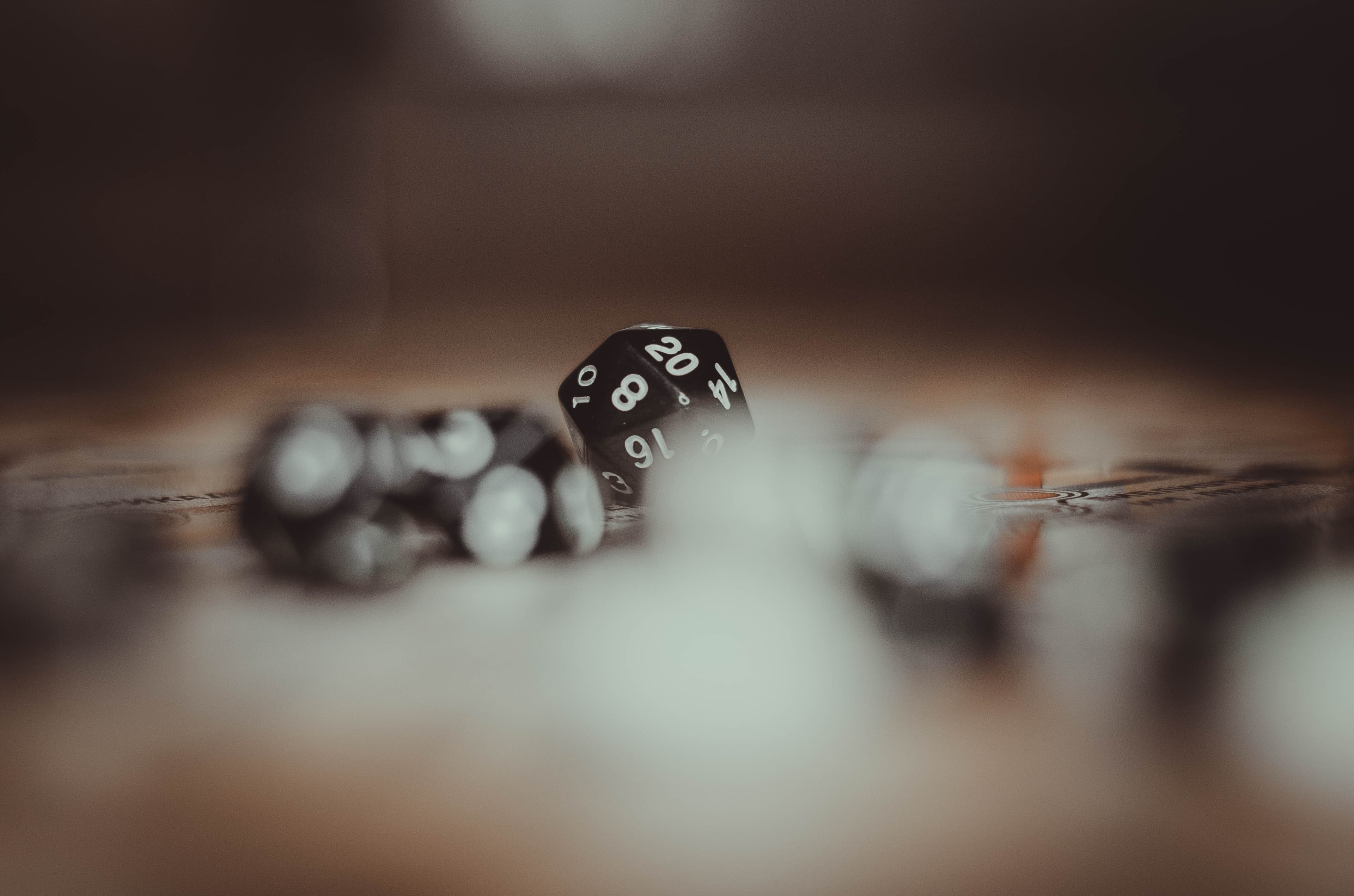 Artistic photo of multi-sided gaming dice in a blurred setting, highlighting the number 20.