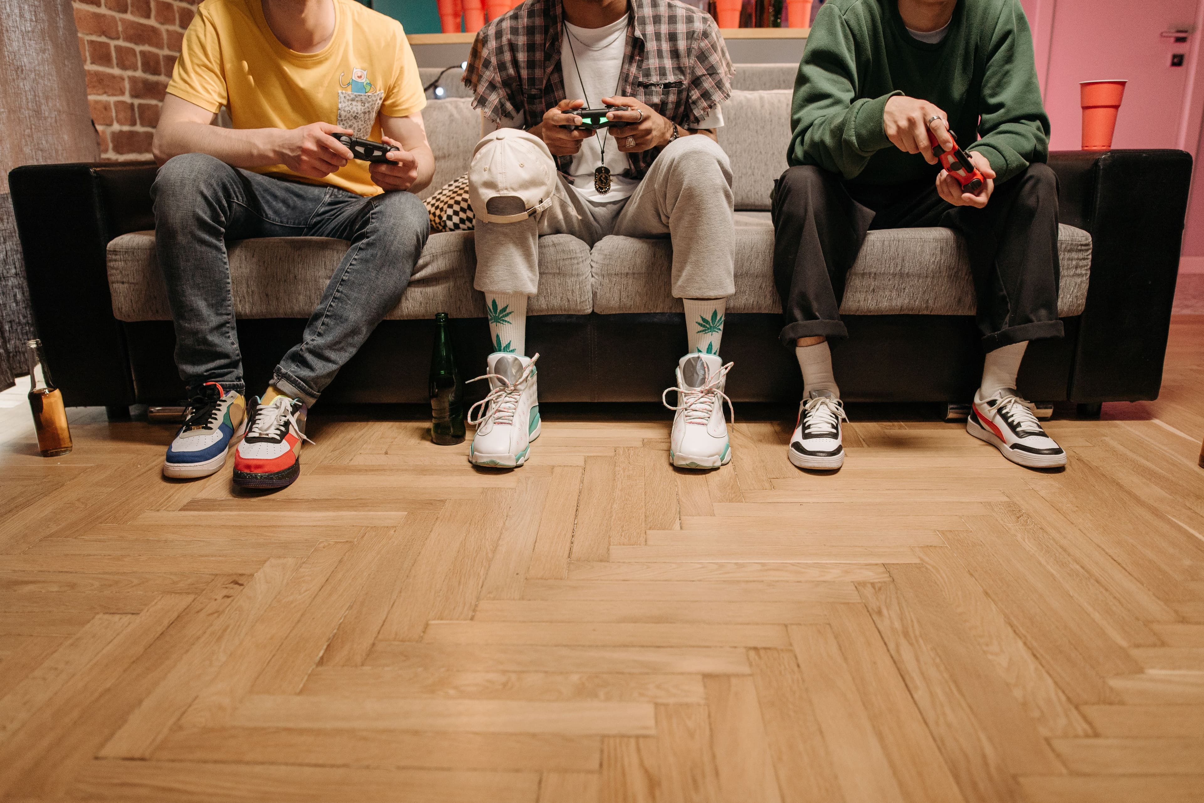 Three men sitting on a sofa playing video games, focused and enjoying the game.